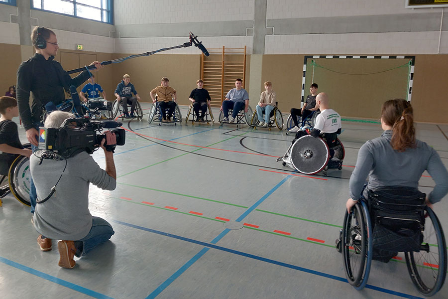Einführung in Rollstuhlsport vor laufender MDR-Kamera